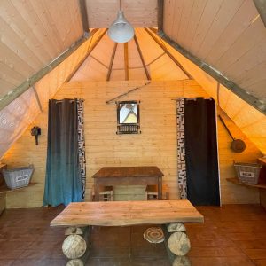 Intérieur dune cabane en bois à Basse-Normandie, avec table en rondins et lumière chaleureuse.