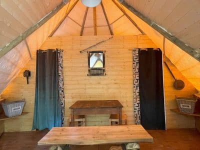 Intérieur dune cabane en bois à Basse-Normandie, avec table en rondins et lumière chaleureuse.