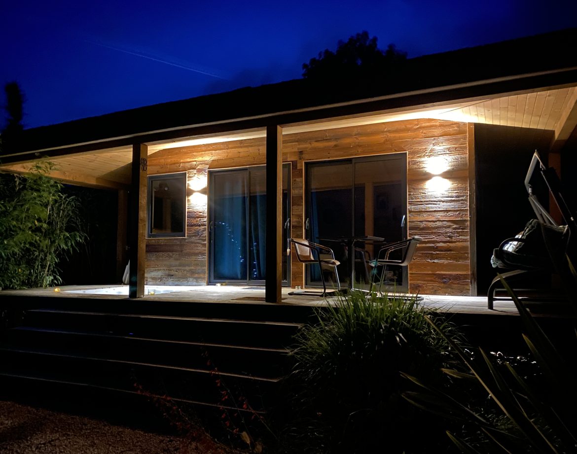 Cabane en bois illuminée la nuit, offrant une ambiance chaleureuse et accueillante.