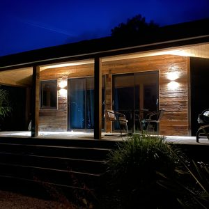 Cabane en bois illuminée la nuit, offrant une ambiance chaleureuse et accueillante.