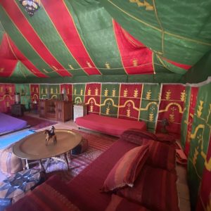 Tente berbère colorée avec coussins rouges et verts, ambiance chaleureuse et accueillante.