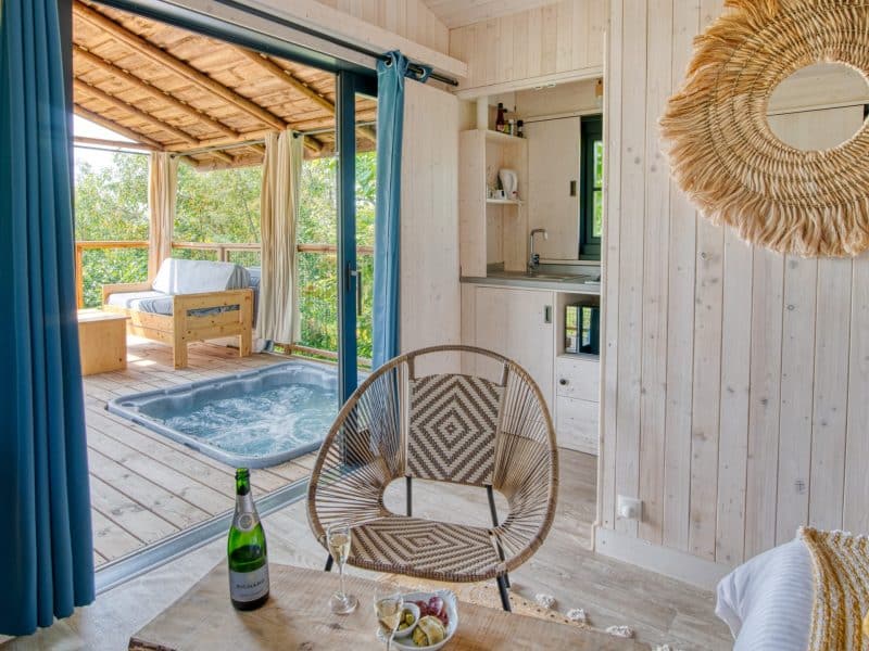 Cabane en bois avec jacuzzi, vue sur la nature et décoration chaleureuse.