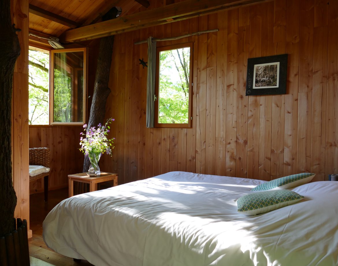 Chalet en bois à Limousin, avec un lit confortable et des fenêtres donnant sur la nature.