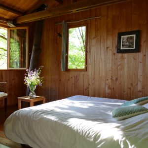 Chalet en bois à Limousin, avec un lit confortable et des fenêtres donnant sur la nature.