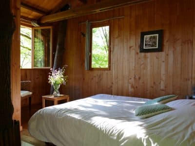 Chalet en bois à Limousin, avec un lit confortable et des fenêtres donnant sur la nature.