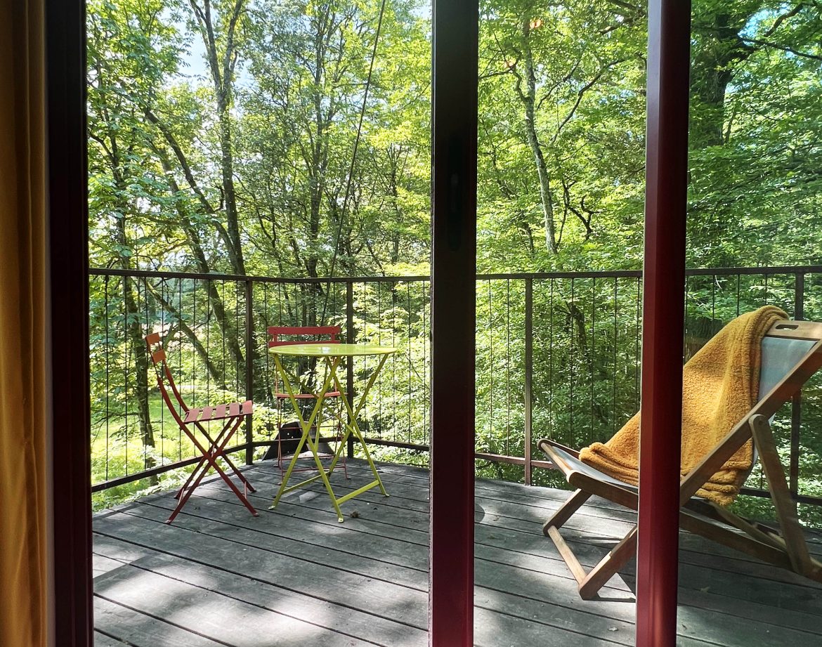 Cabane perchée en Bourgogne avec terrasse en bois et vue sur la forêt verdoyante.