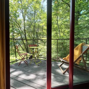 Cabane perchée en Bourgogne avec terrasse en bois et vue sur la forêt verdoyante.