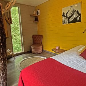 Chambre insolite en Bourgogne, murs jaunes et vue sur la nature depuis la fenêtre.