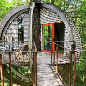 Cabane suspendue en bois, perchée dans les arbres avec vue sur la forêt verdoyante.