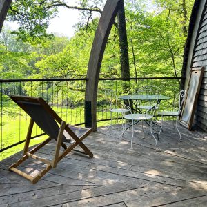 Hébergement insolite en Bourgogne : terrasse en bois avec vue sur la nature verdoyante.