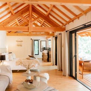 Chalet en bois lumineux avec poutres apparentes et terrasse ensoleillée.