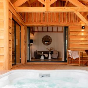 Cabane en bois avec jacuzzi, offrant une vue sur un intérieur chaleureux et moderne.