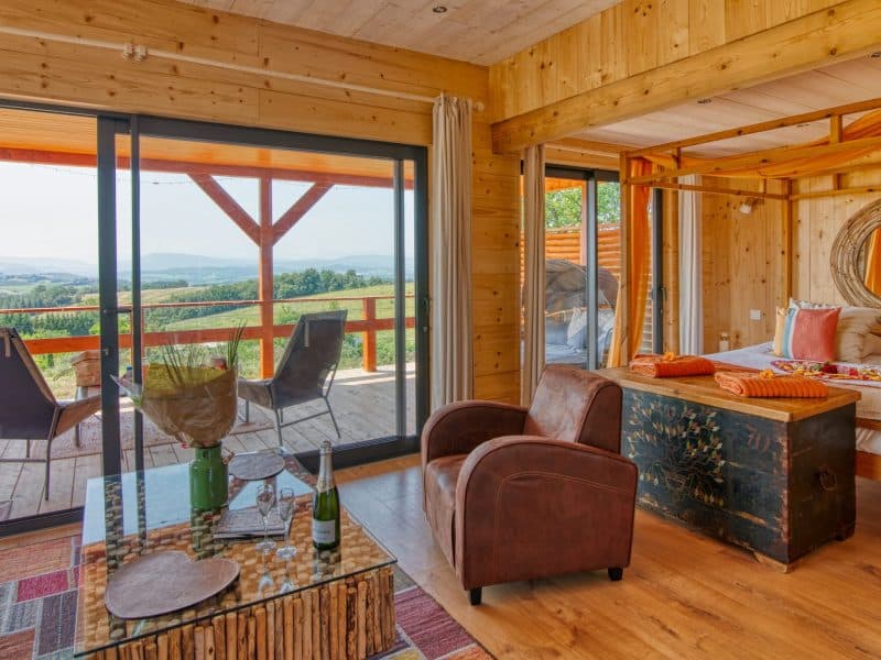 Chalet en bois avec vue panoramique, lit à baldaquin et terrasse accueillante.