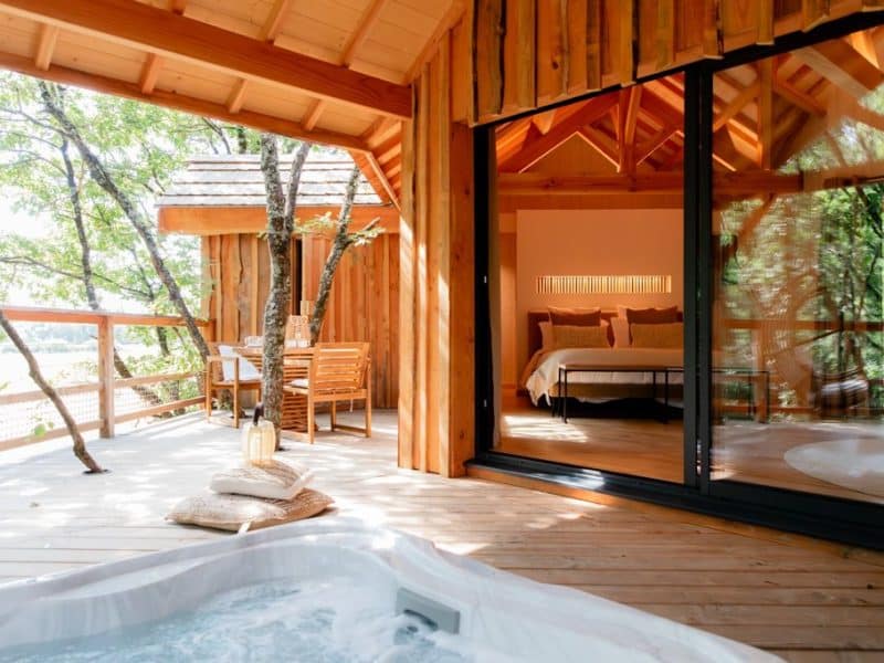 Cabane en bois avec jacuzzi extérieur et vue sur la nature. Ambiance chaleureuse et cosy.