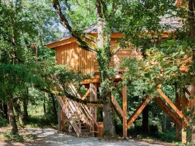 Cabane perchée en bois dans les arbres, entourée de verdure à Midi-Pyrénées.