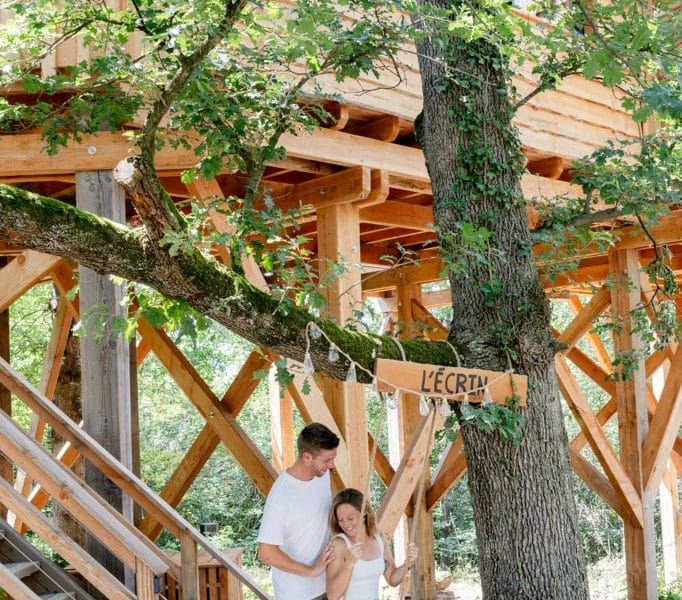 Cabane dans les arbres, couple sous un arbre, ambiance naturelle et chaleureuse.
