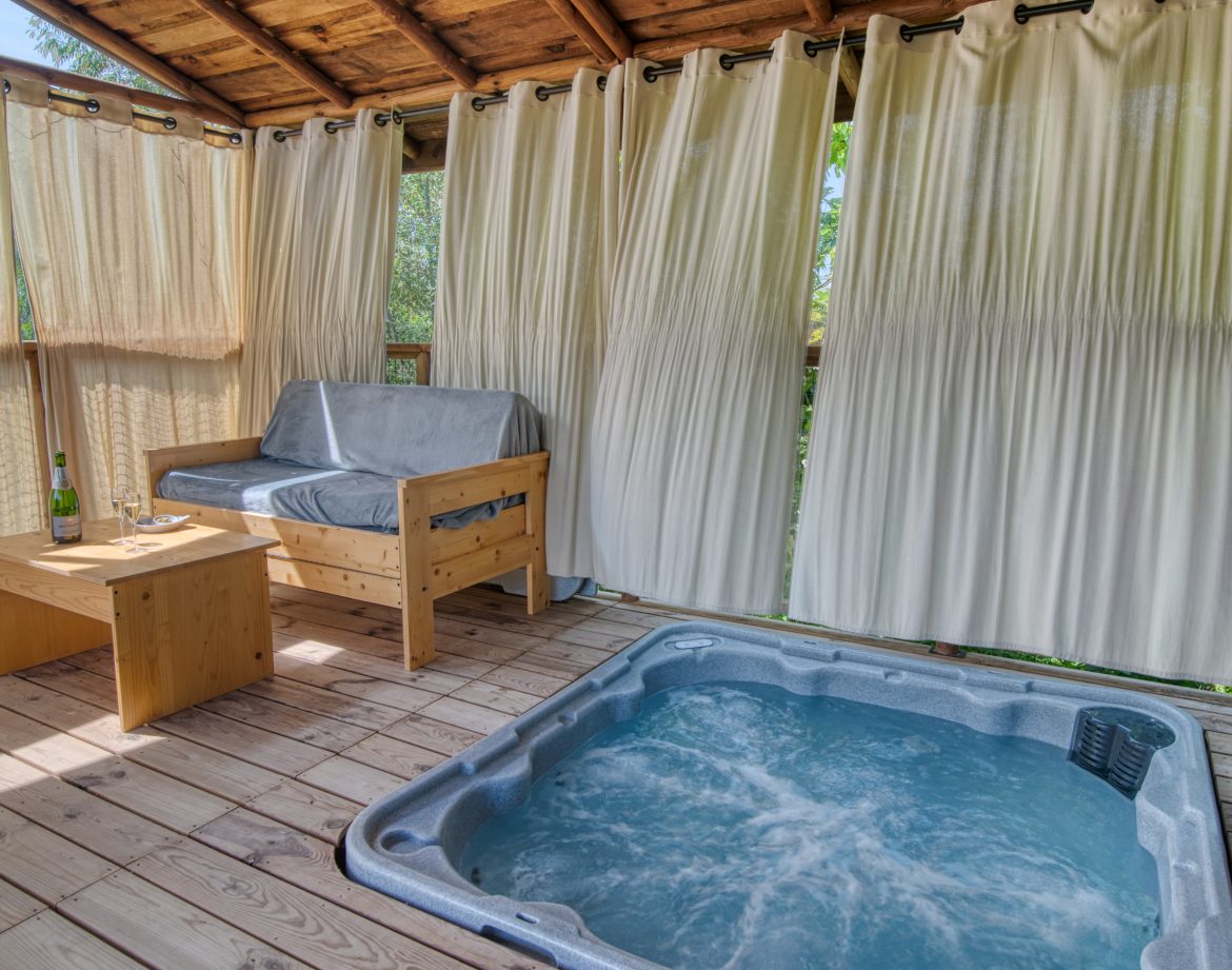 Cabane perchée avec jacuzzi, offrant une vue sur la nature environnante.