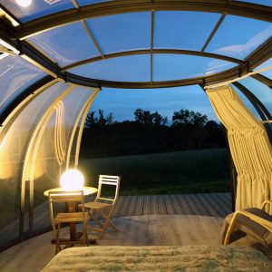Hébergement insolite en bulle transparente, vue sur la nature au crépuscule.