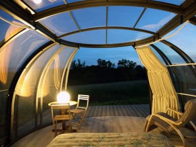 Hébergement insolite en bulle transparente, vue sur la nature au crépuscule.