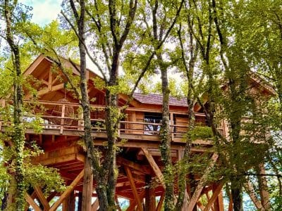 Cabane perchée dans les arbres, entourée de verdure luxuriante à Midi-Pyrénées.