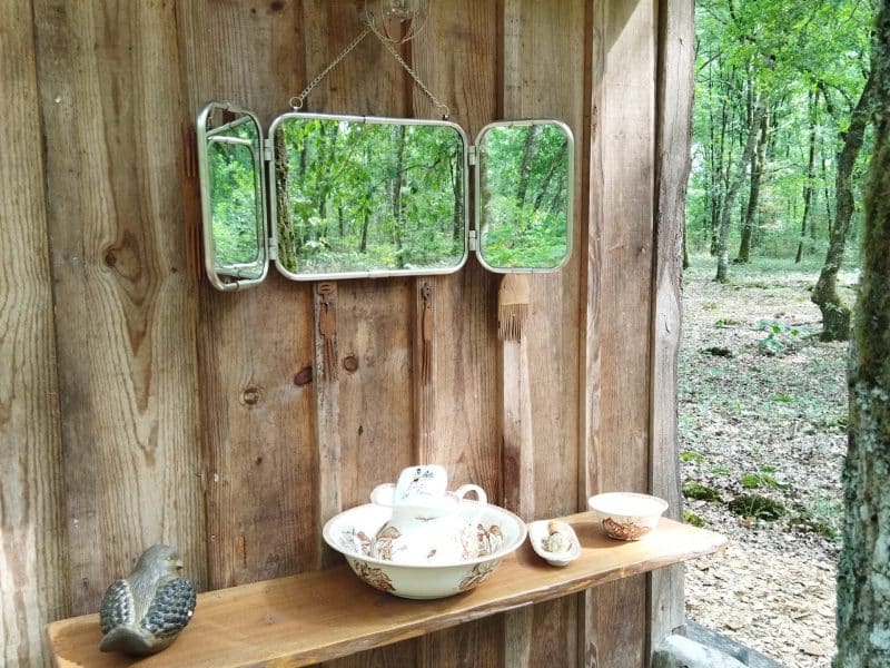 Cabane en bois avec un miroir vintage et des objets décoratifs sur une étagère.
