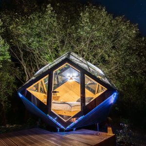 Cabane en bois suspendue, éclairage doux et vue sur les étoiles dans la nature.
