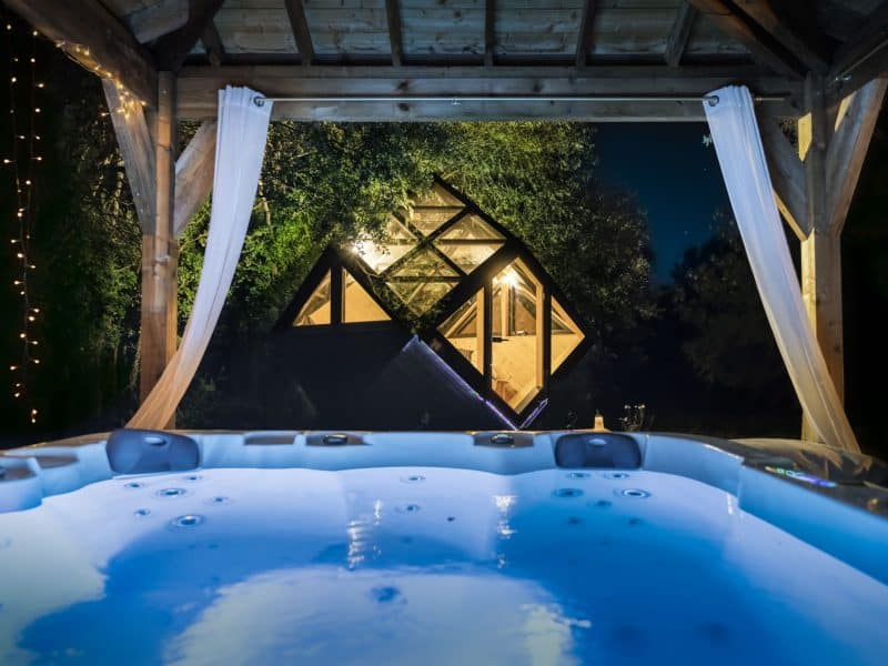 Hébergement insolite en Languedoc-Roussillon avec jacuzzi et vue sur une cabane lumineuse.