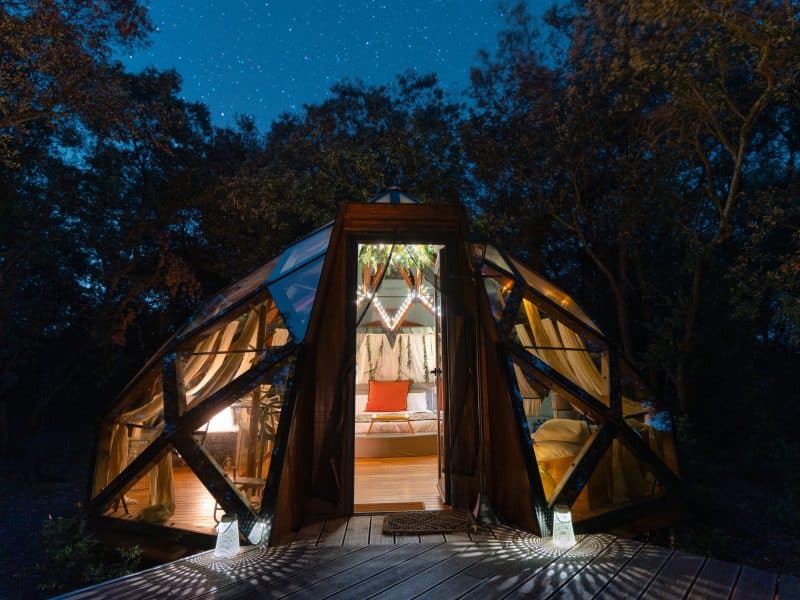 Dôme en bois lumineux sous les étoiles, offrant une vue unique sur la nature.