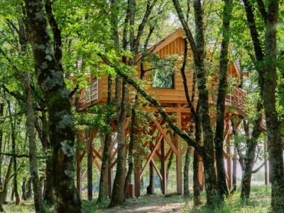 Cabane perchée en bois, entourée darbres verdoyants à Midi-Pyrénées.