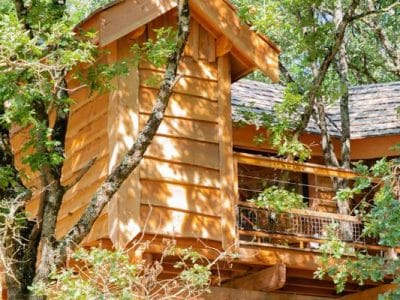 Cabane perchée en bois, entourée darbres verdoyants à Midi-Pyrénées.