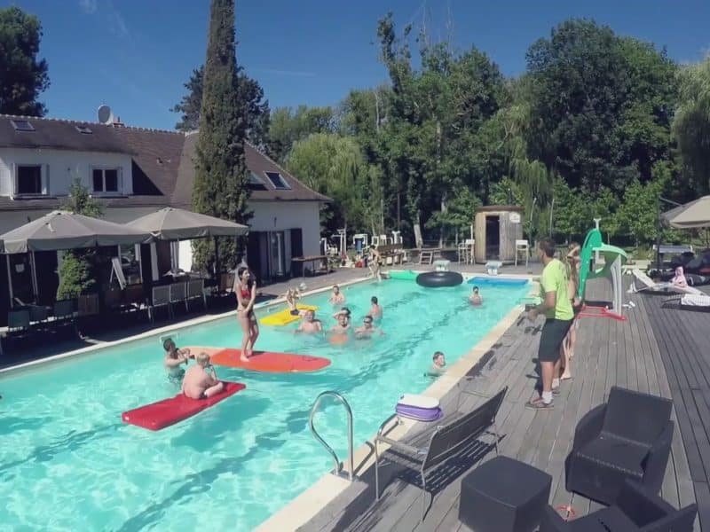 Hébergement touristique avec piscine, entouré de verdure et dactivités aquatiques.