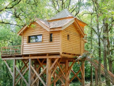 Cabane perchée en bois, entourée darbres verdoyants à Midi-Pyrénées.