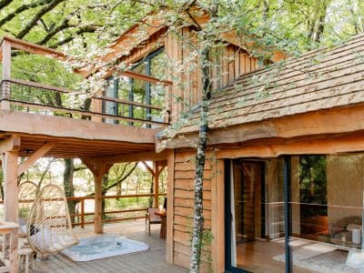 Cabane perchée en bois à Midi-Pyrénées, entourée darbres verdoyants.