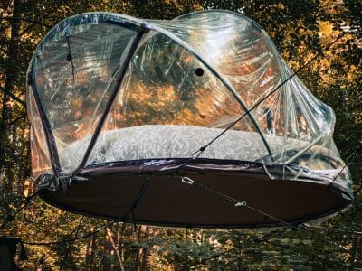 Cabane suspendue en pleine forêt, offrant une vue panoramique sur la nature.