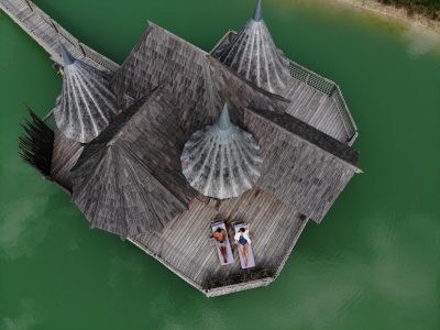 Hébergement insolite en Aquitaine : cabanes en bois sur pilotis au bord dun lac turquoise.