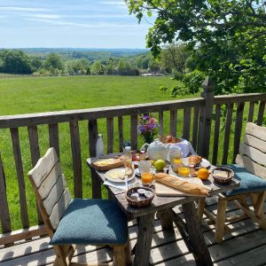 Hébergement insolite en Aquitaine : terrasse en bois avec vue sur la campagne verdoyante.