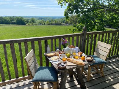 Hébergement insolite en Aquitaine : terrasse en bois avec vue sur la campagne verdoyante.