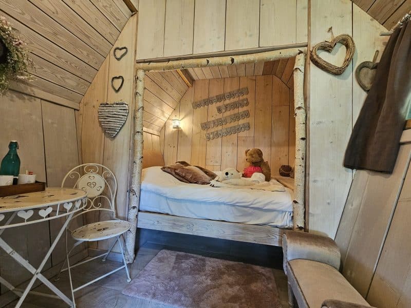 Chalet en bois chaleureux avec lit douillet et décor romantique en cœur.
