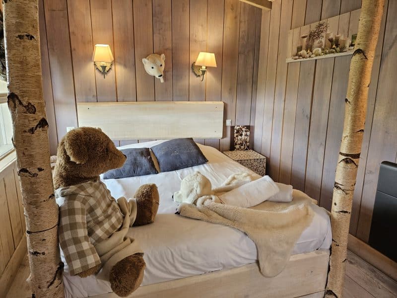 Chalet douillet avec lit confortable, décoré de bois et dours en peluche.