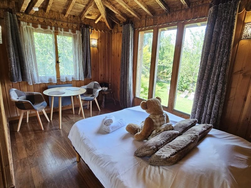 Chalet en bois chaleureux avec lit douillet et vue sur le jardin verdoyant.