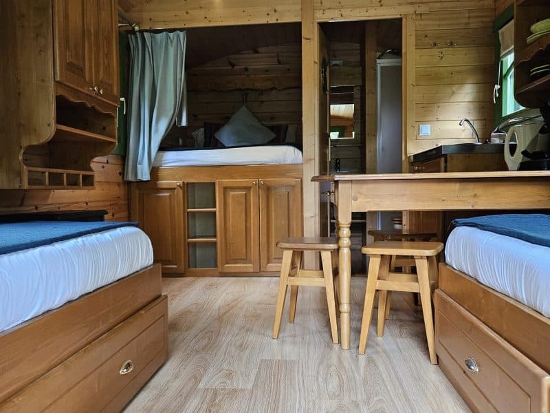 Intérieur dun chalet en bois, avec lits jumeaux et table en bois clair.