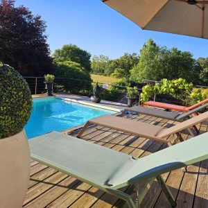 Hébergement insolite en Midi-Pyrénées avec piscine et chaises longues au bord.