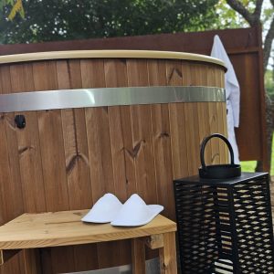 Hébergement insolite en Midi-Pyrénées avec un bain nordique en bois et des chaussons blancs.