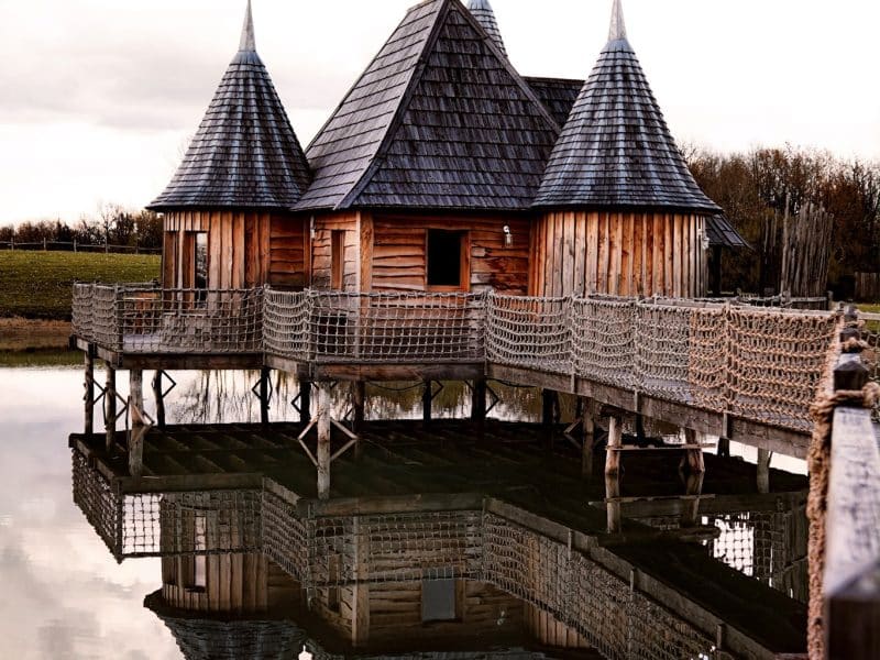 Cabane sur pilotis en Aquitaine, avec toits pointus et reflet dans leau.