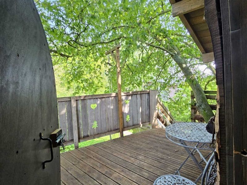 Cabane dans les arbres avec terrasse en bois et mobilier de jardin élégant.