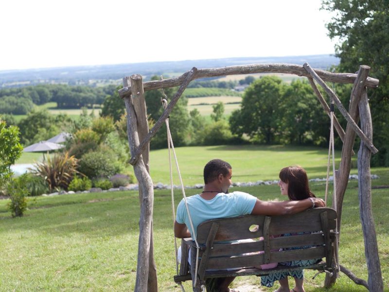 Un gîte romantique avec balançoire en bois, vue panoramique sur la campagne.