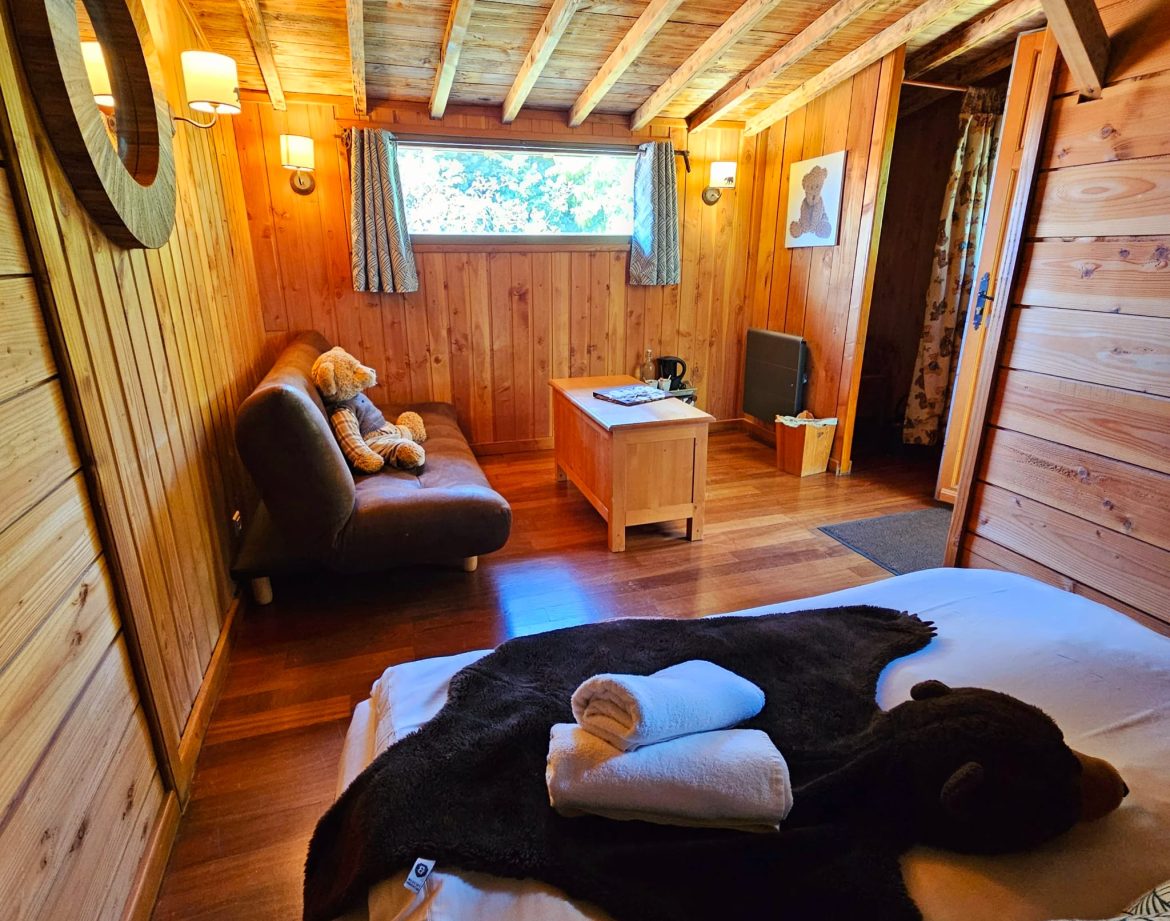 Chalet en bois chaleureux avec lit douillet et décor naturel apaisant.