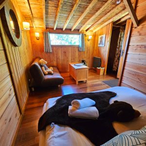 Chalet en bois chaleureux avec lit douillet et décor naturel apaisant.