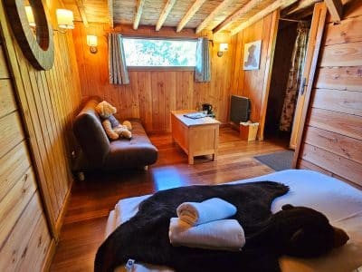 Chalet en bois chaleureux avec lit douillet et décor naturel apaisant.
