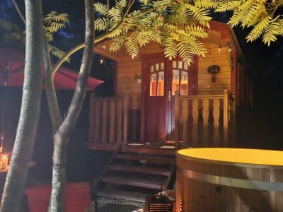 Cabane en bois charmante avec éclairage chaleureux et jacuzzi extérieur.